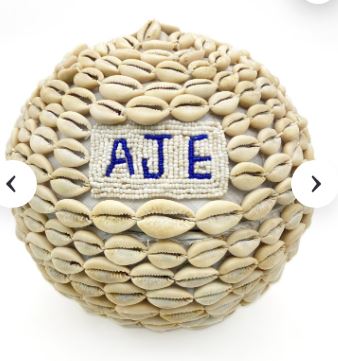 Cowrie shell vessel marked with the word Aje as a symbol of wealth, exchange, and prosperity offerings
