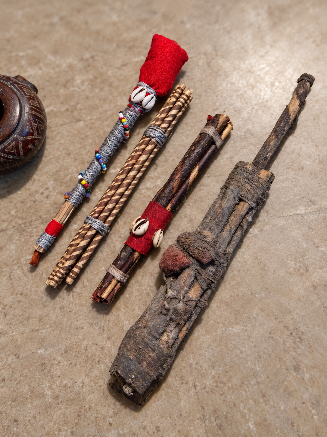 AI-assisted illustration of four ancestral bundle forms arranged diagonally, with a small African pot at the left and the large Atori with an attached handle at the right.